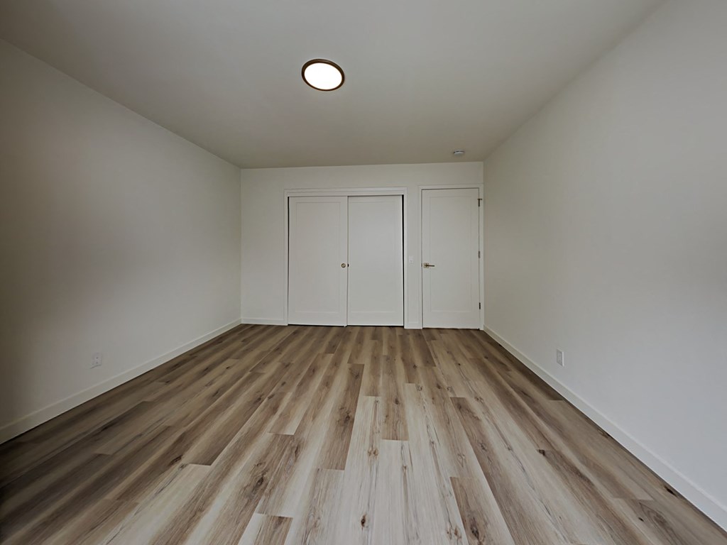 an empty living room with wood floors and white walls