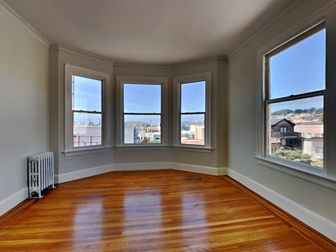a living room with a wood floor and four windows