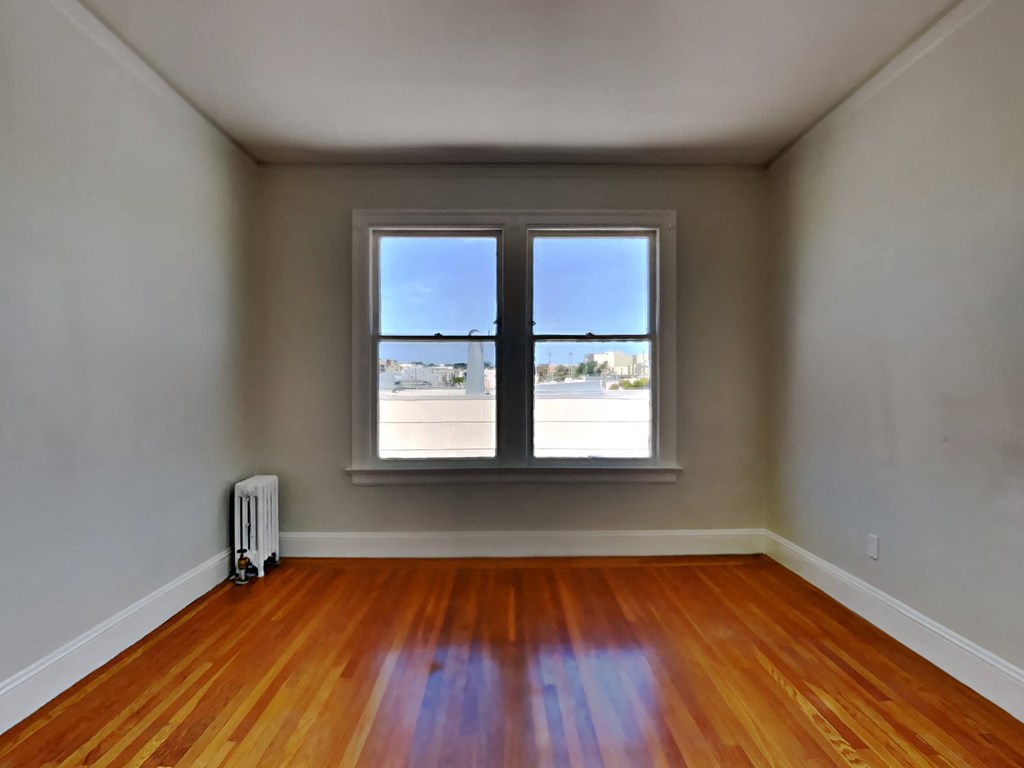 an empty room with a window and wooden floors