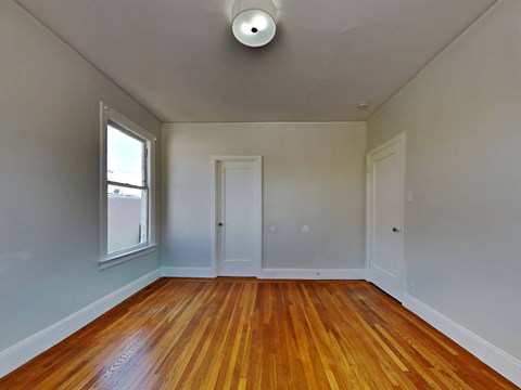 an empty living room with wood floors and a window