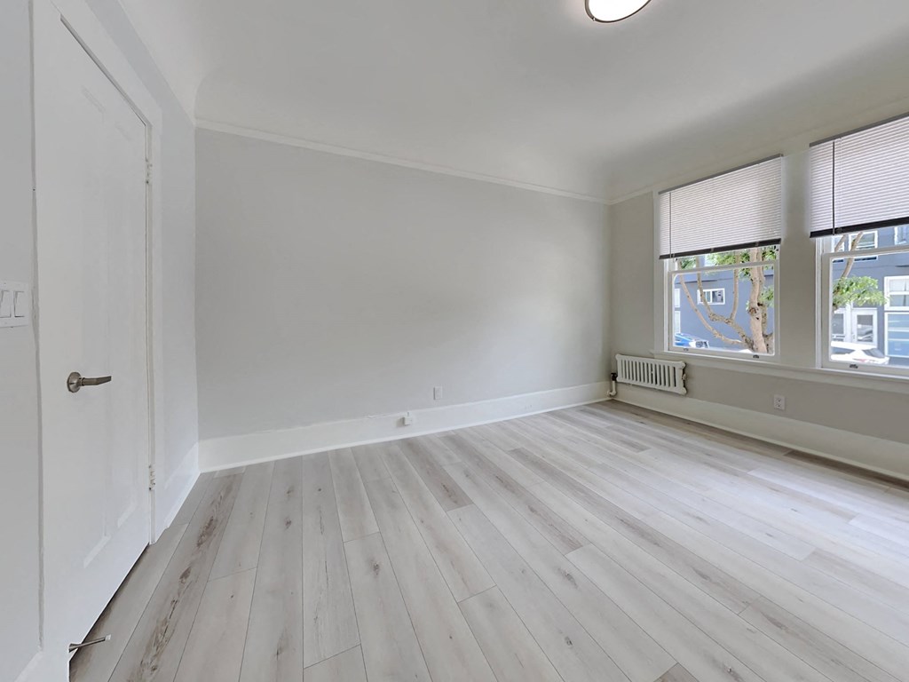 an empty room with white walls and wooden floors