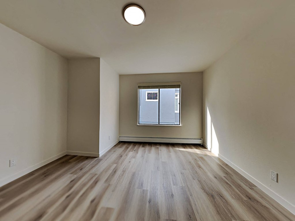 an empty living room with wood floors and a window
