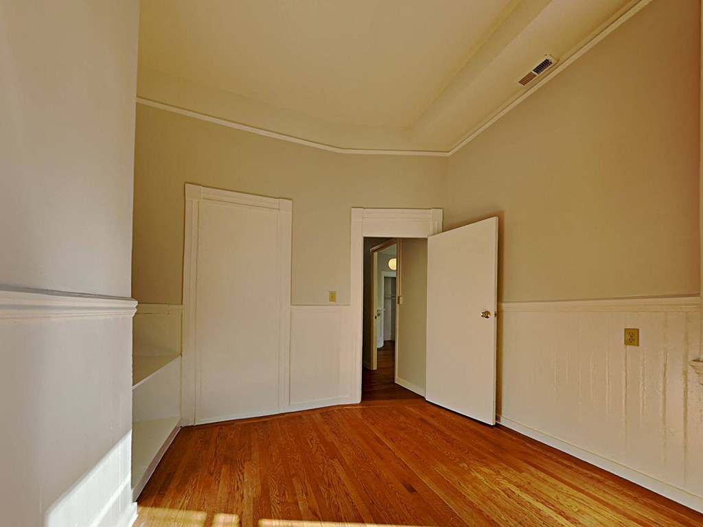 a bedroom with wood floors and white walls