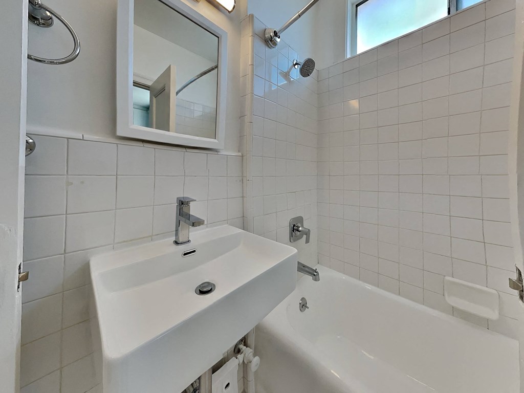 a white bathroom with a sink and a tub