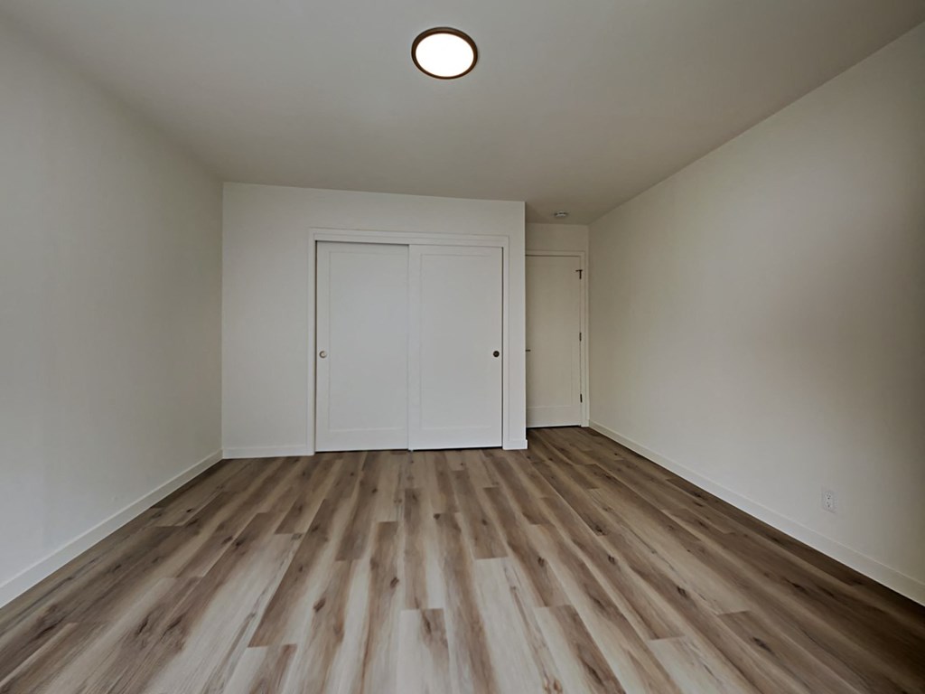 an empty living room with white walls and wood flooring
