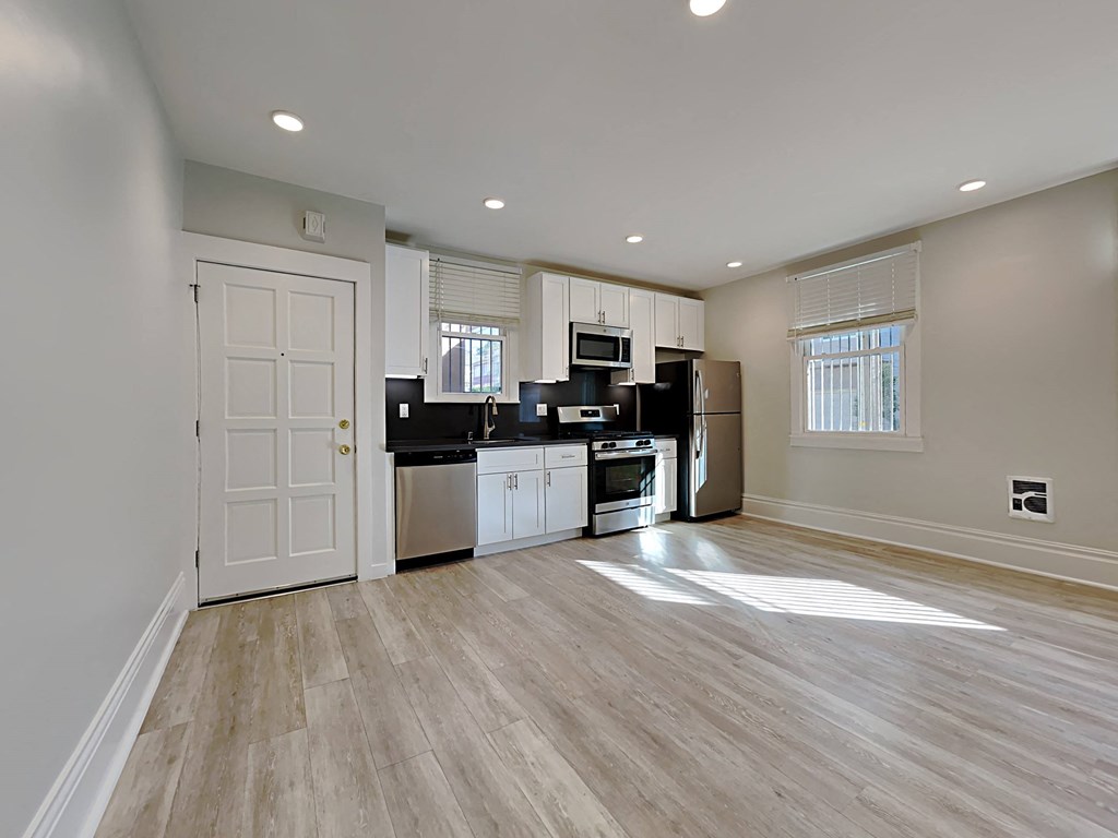 an empty living room with a kitchen and a door