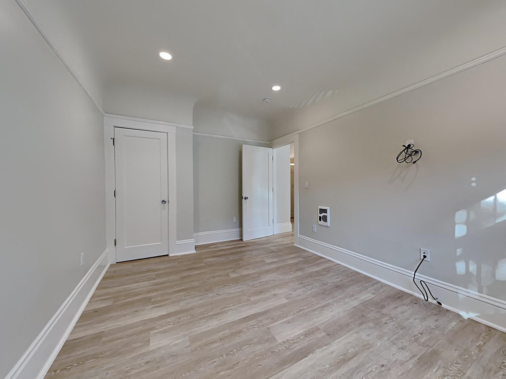 a newly renovated living room with white walls and wood flooring
