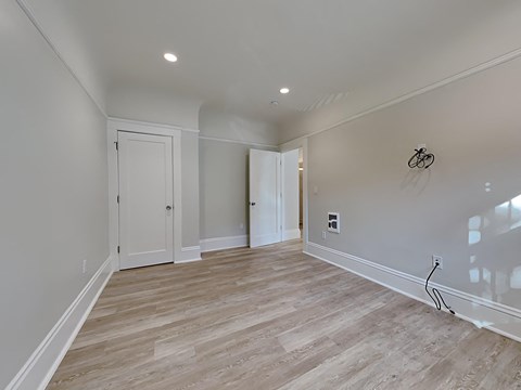 a newly renovated living room with white walls and wood flooring