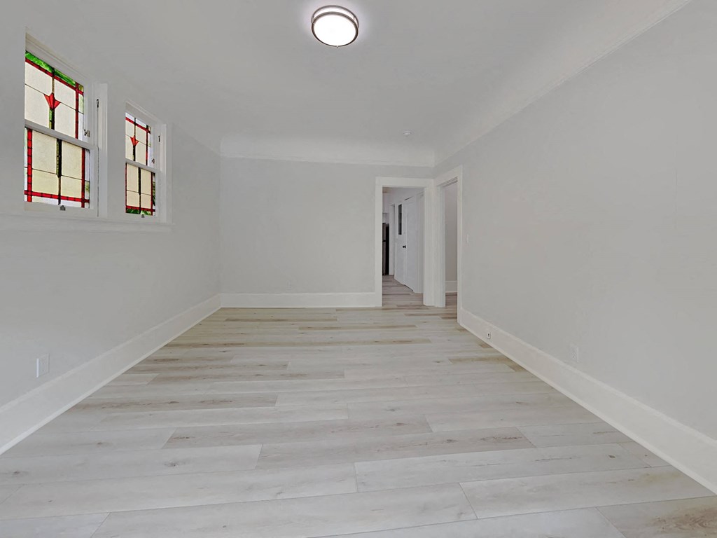 an empty room with white walls and wooden floors and stained glass windows