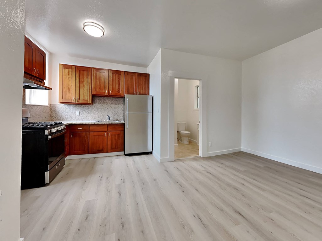 an empty kitchen with wooden cabinets and a stainless steel refrigerator