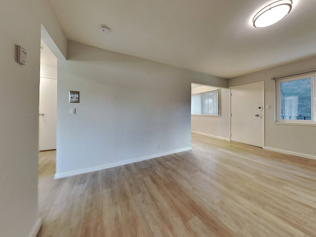 an empty living room with white walls and wood floors