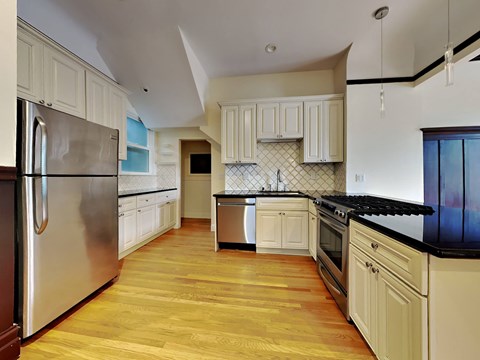 A kitchen with wooden floors and white cabinets.