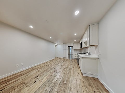 an open living room and kitchen with wood floors and white walls