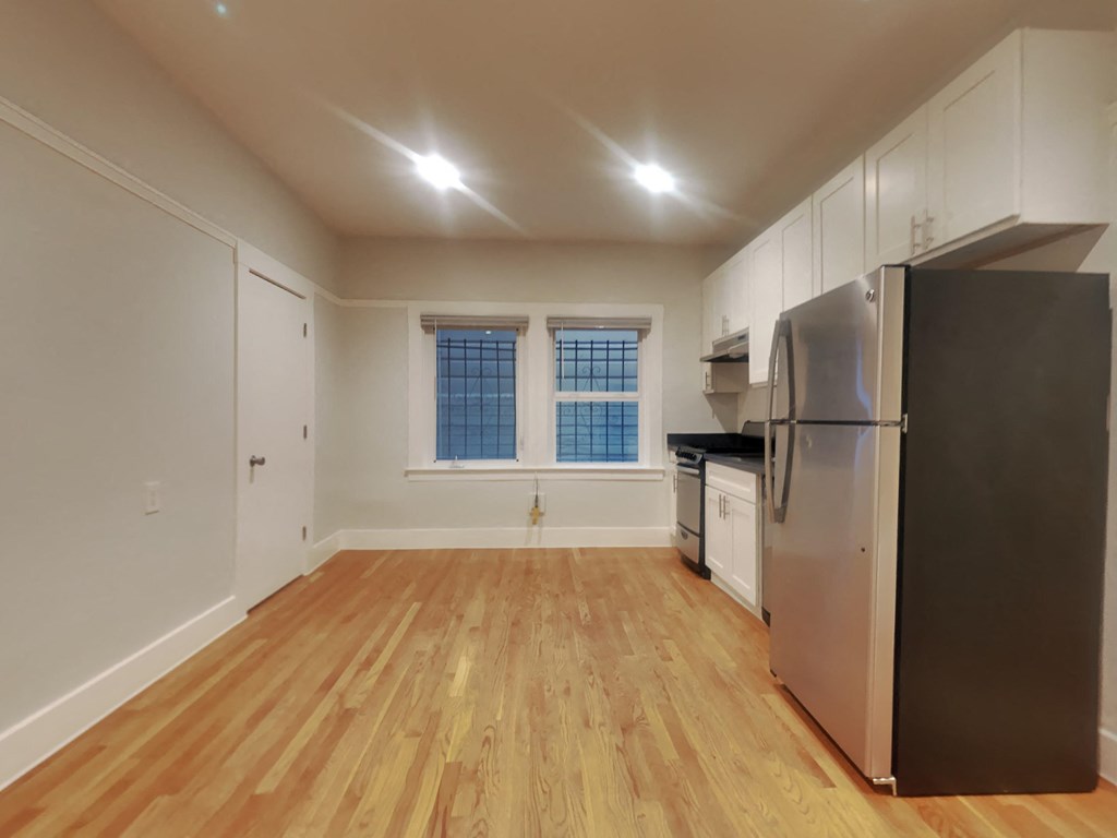 an empty kitchen with stainless steel appliances and wood floors