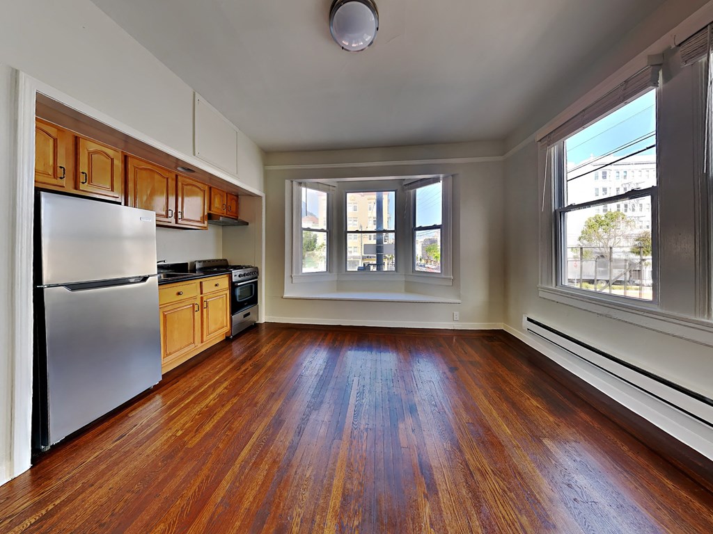 an empty kitchen with wood floors and a large window