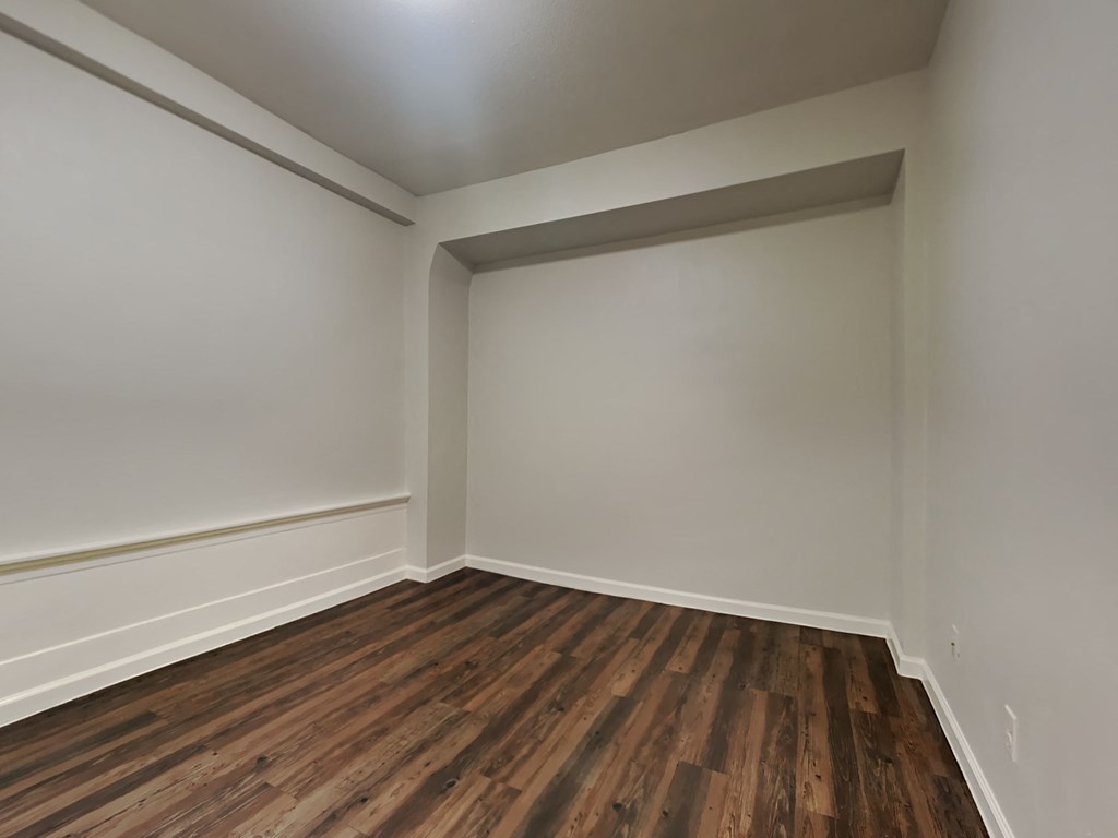 an empty room with wood floors and white walls