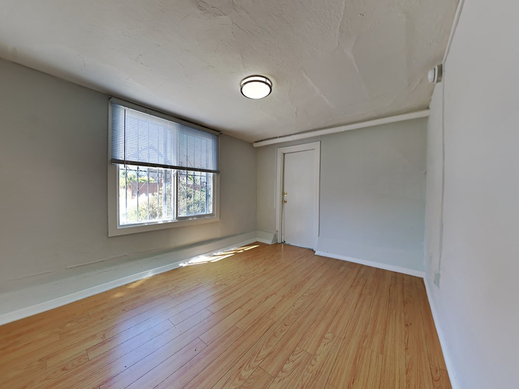 an empty living room with wood floors and a window