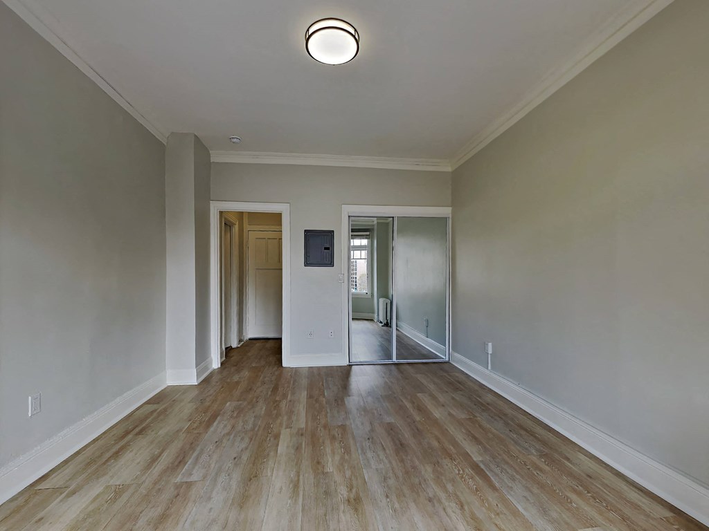 a spacious living room with white walls and wood floors