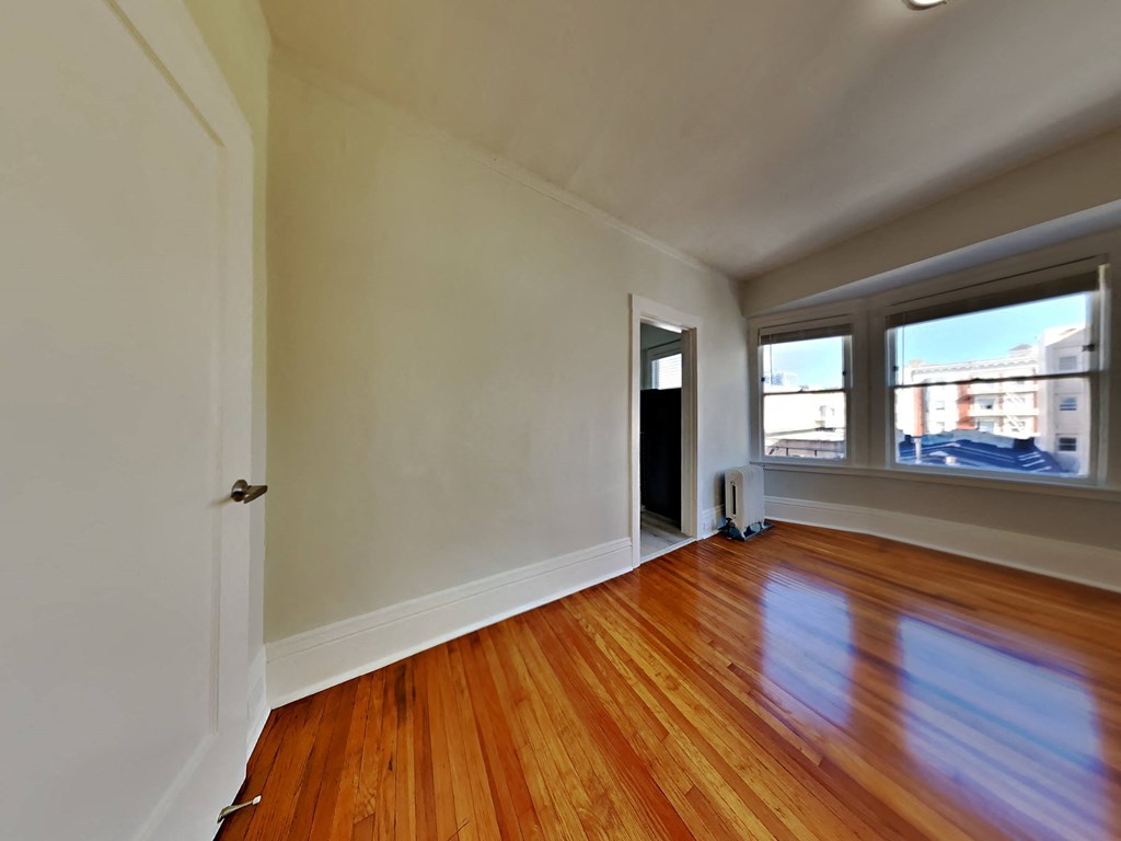 an empty living room with wood floors and a window