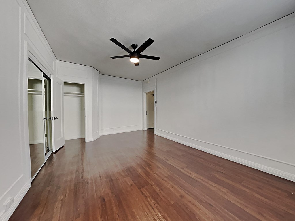 an empty living room with white walls and a ceiling fan