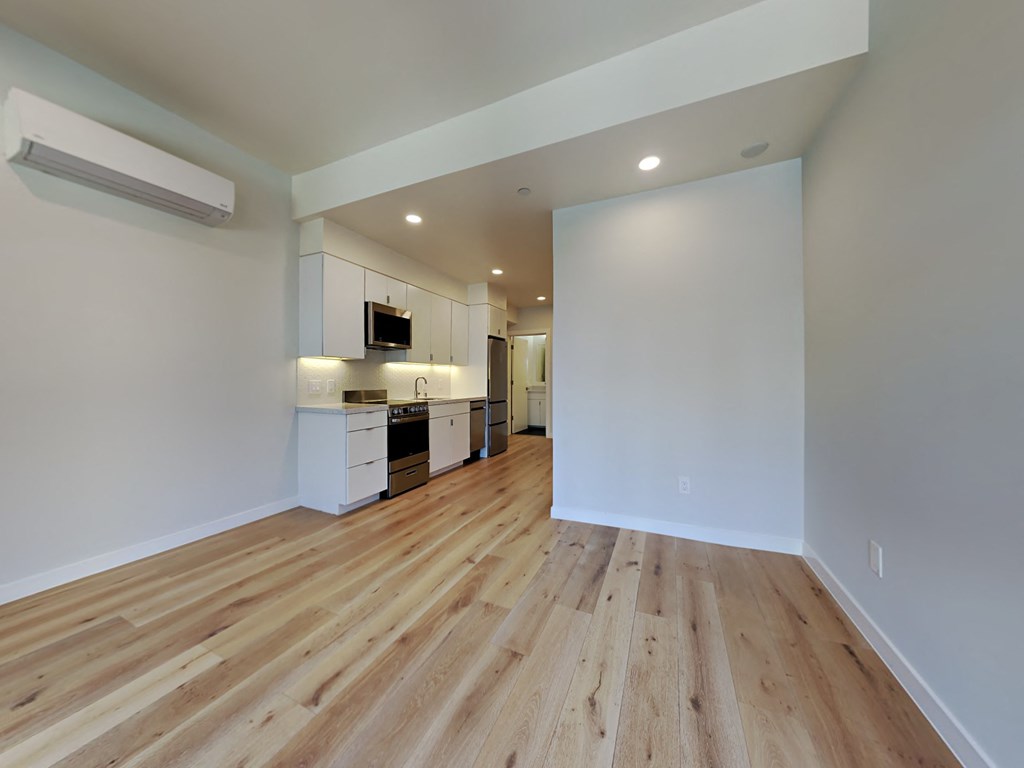 a living room and kitchen with wood floors and white walls
