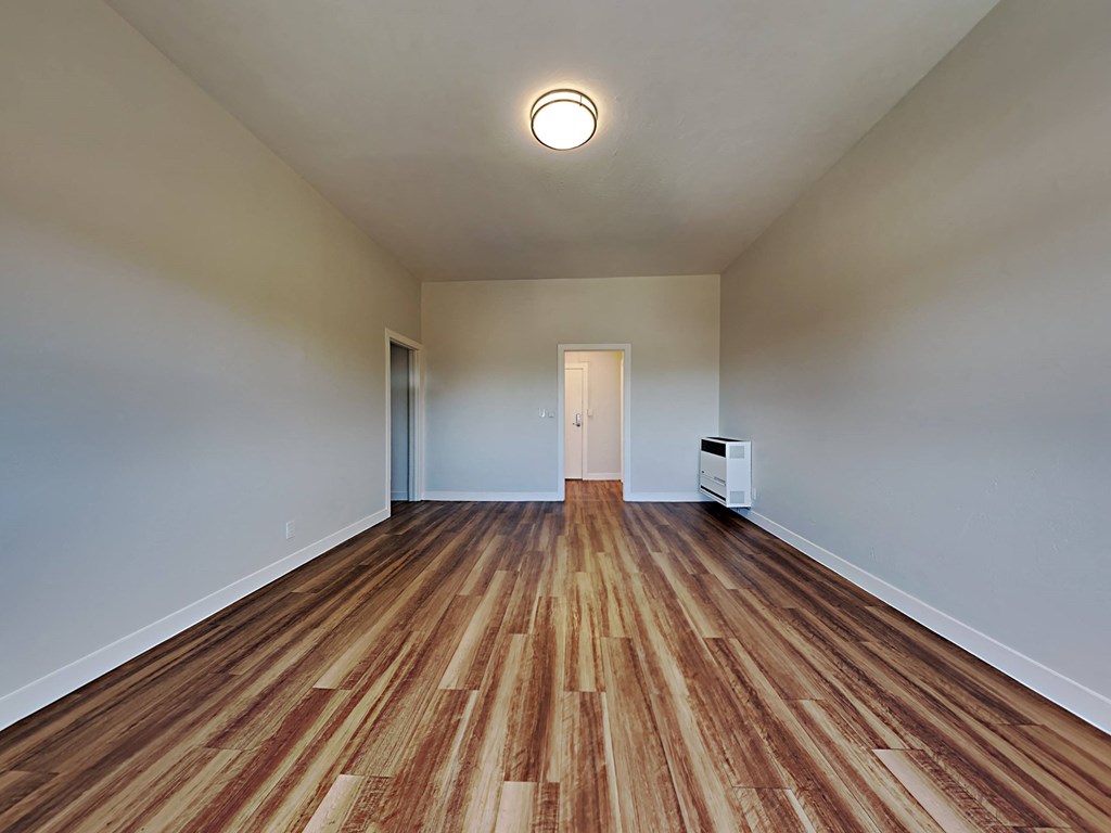 a spacious living room with wood flooring and white walls