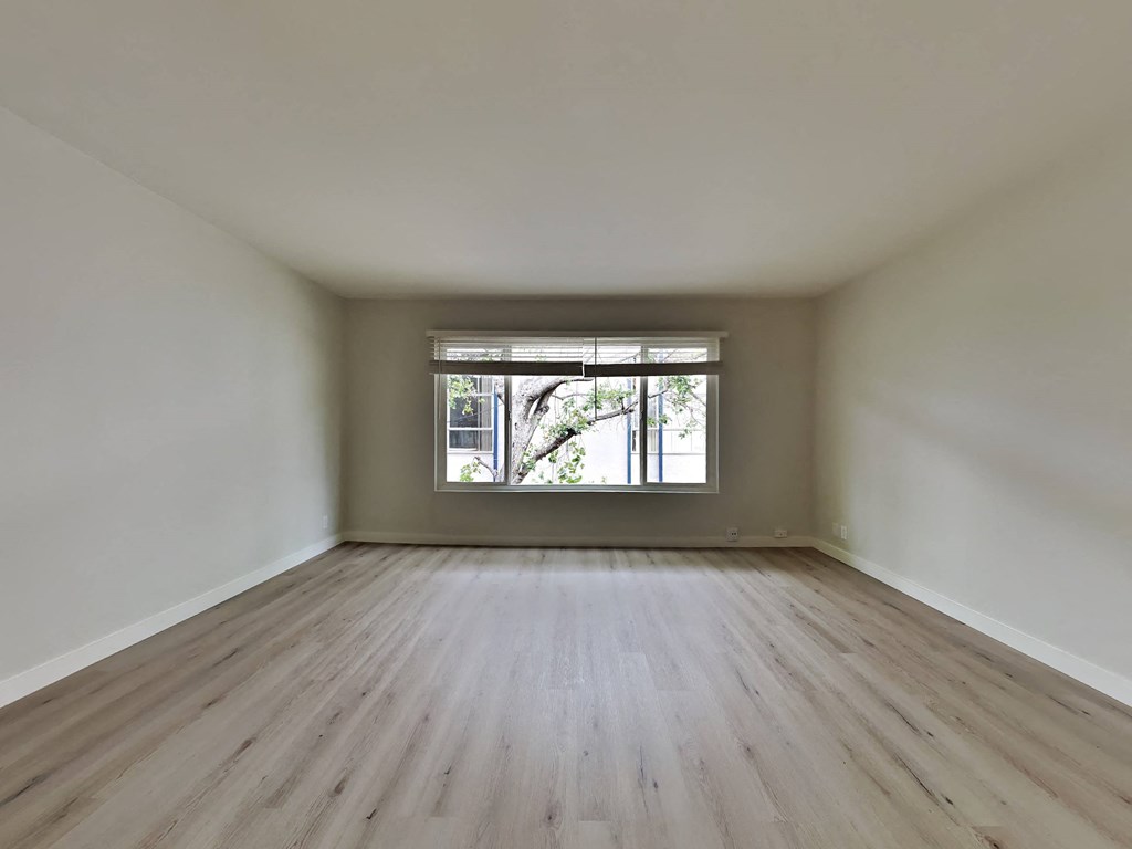 an empty room with wooden floors and a window