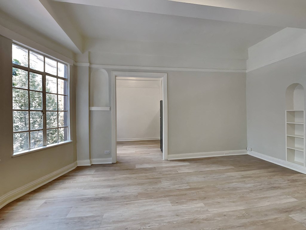 an empty room with white walls and a large window and wooden floors