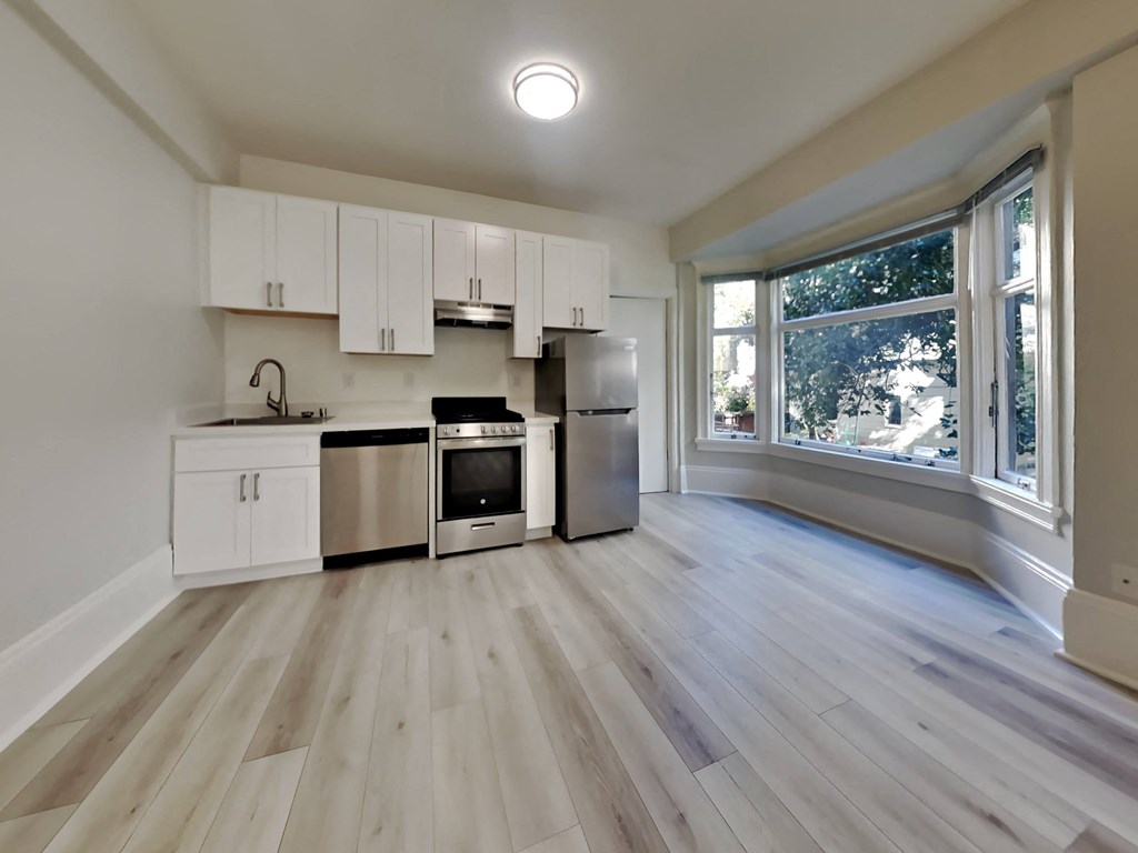 an empty kitchen with white cabinets and stainless steel appliances