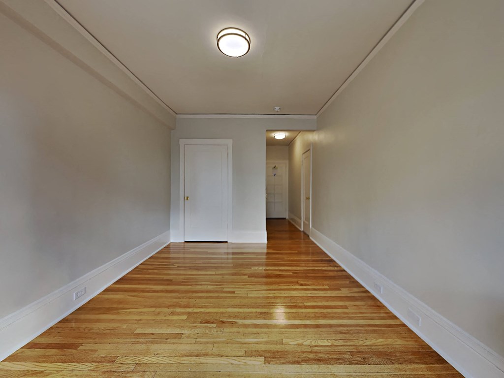 a long hallway with wood floors and white walls and a white door