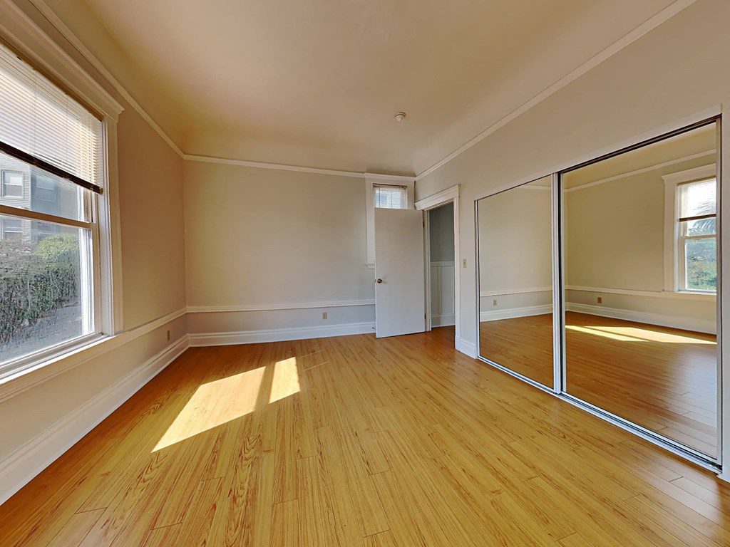the living room of an empty house with a wooden floor and glass doors