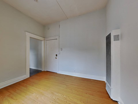 a bedroom with a hard wood floor and white walls