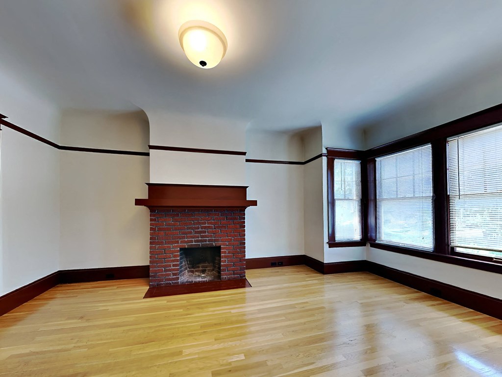a living room with a brick fireplace and a wooden floor