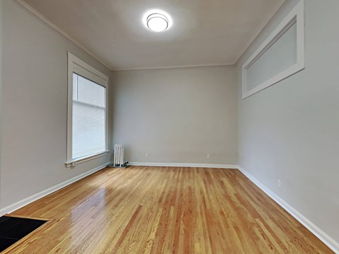 an empty living room with wood floors and a window