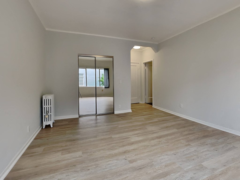 a renovated living room with a white wall and wooden floors