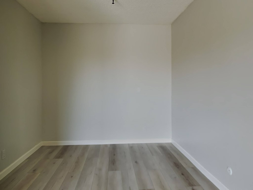 an empty room with white walls and wooden floors