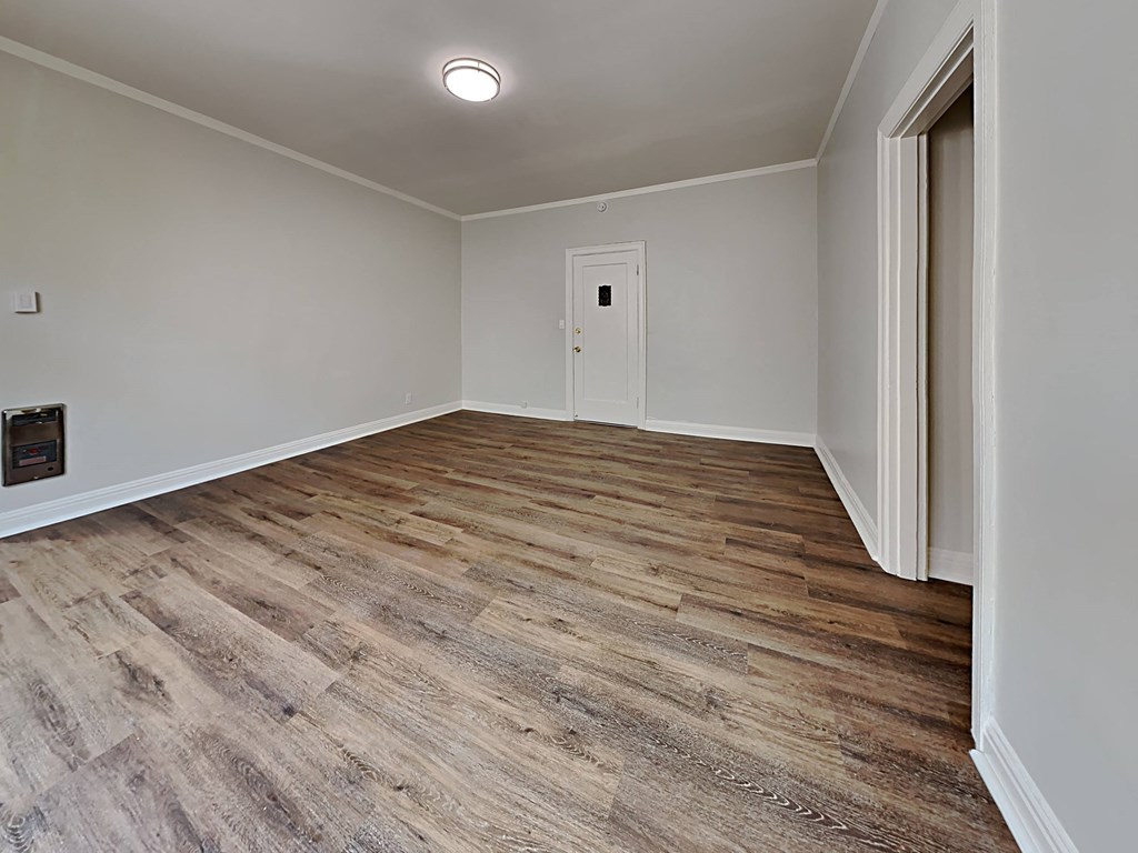 a spacious living room with wood floors and white walls