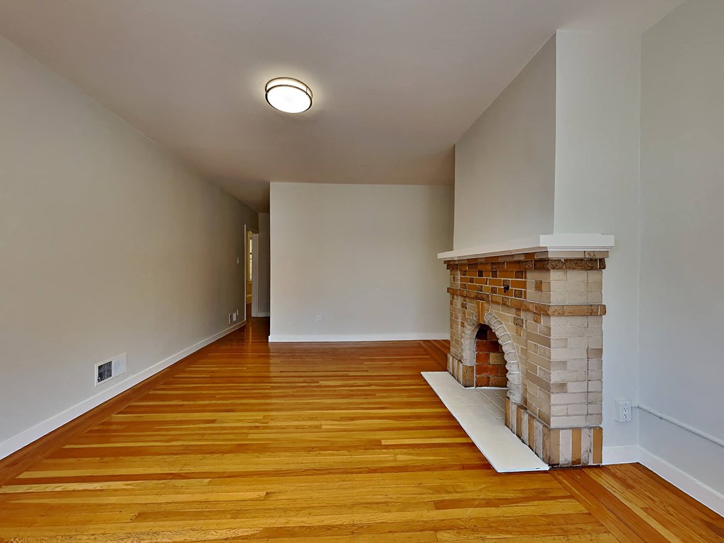 a living room with a brick fireplace and wooden floors