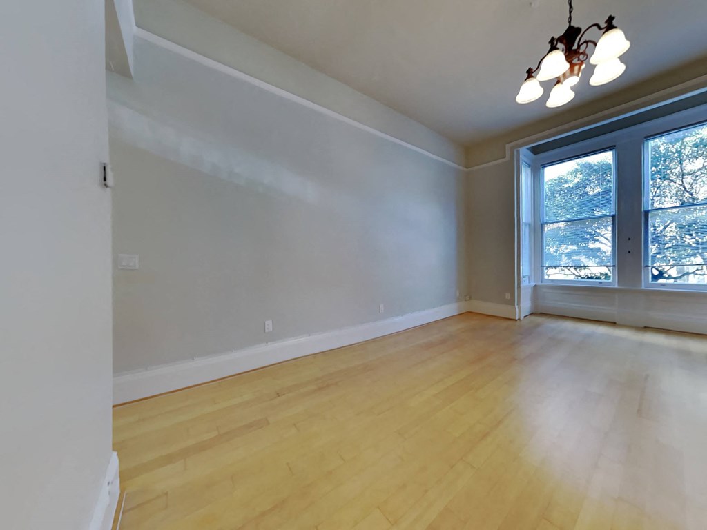 an empty living room with wood floors and a large window