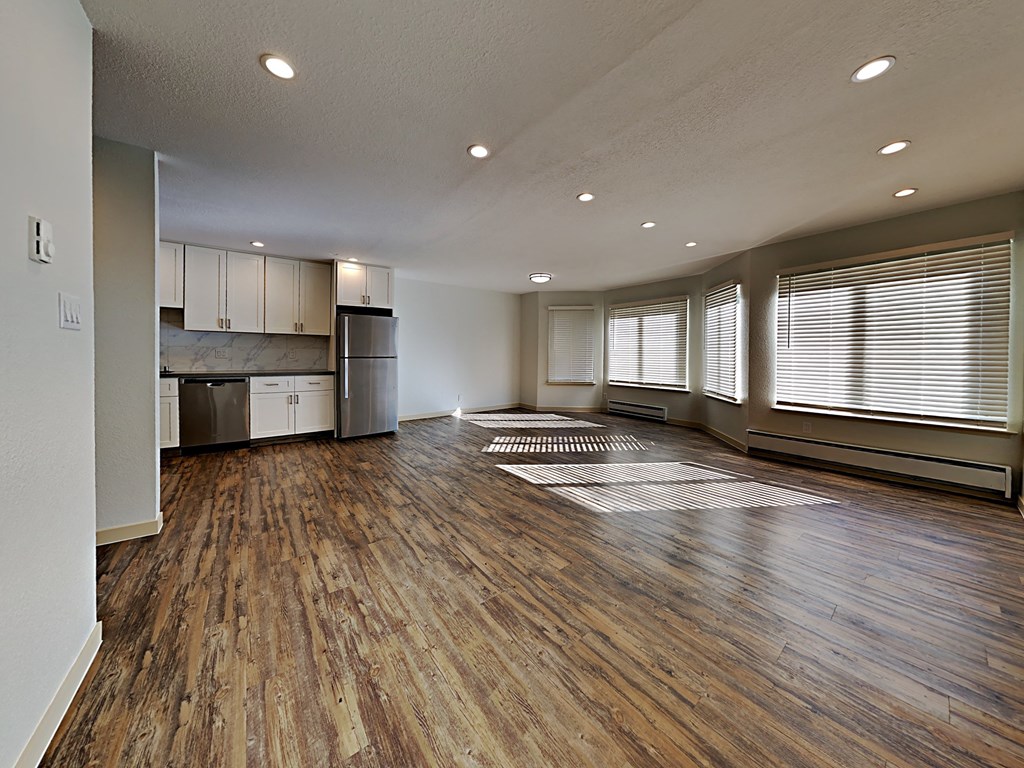 an empty living room and kitchen with wood flooring