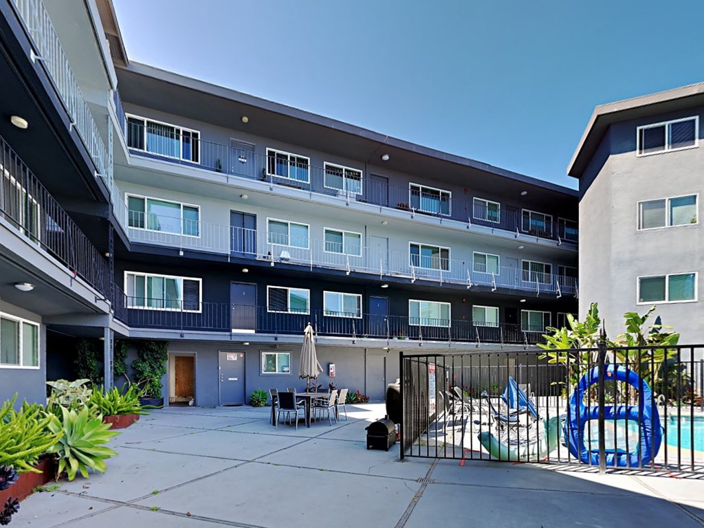 a courtyard with tables and chairs in front of an apartment building