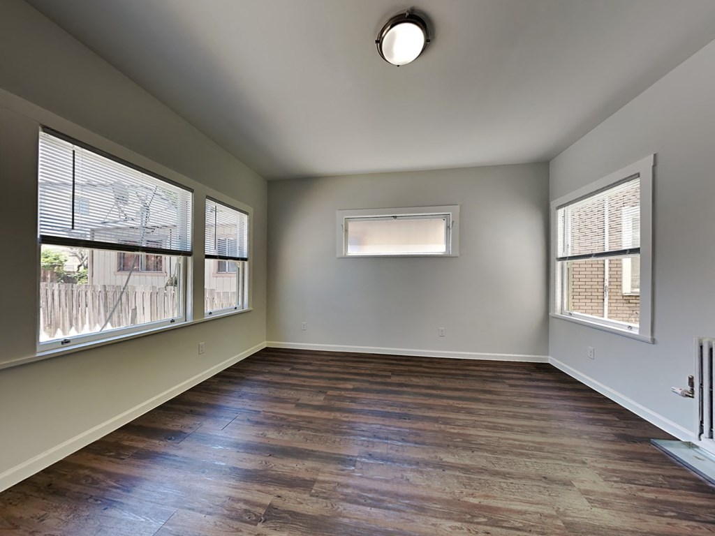 an empty living room with wood floors and large windows