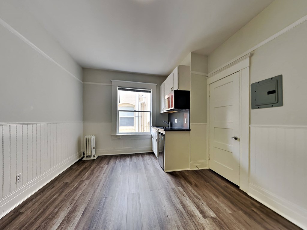an empty living room with wood floors and a window