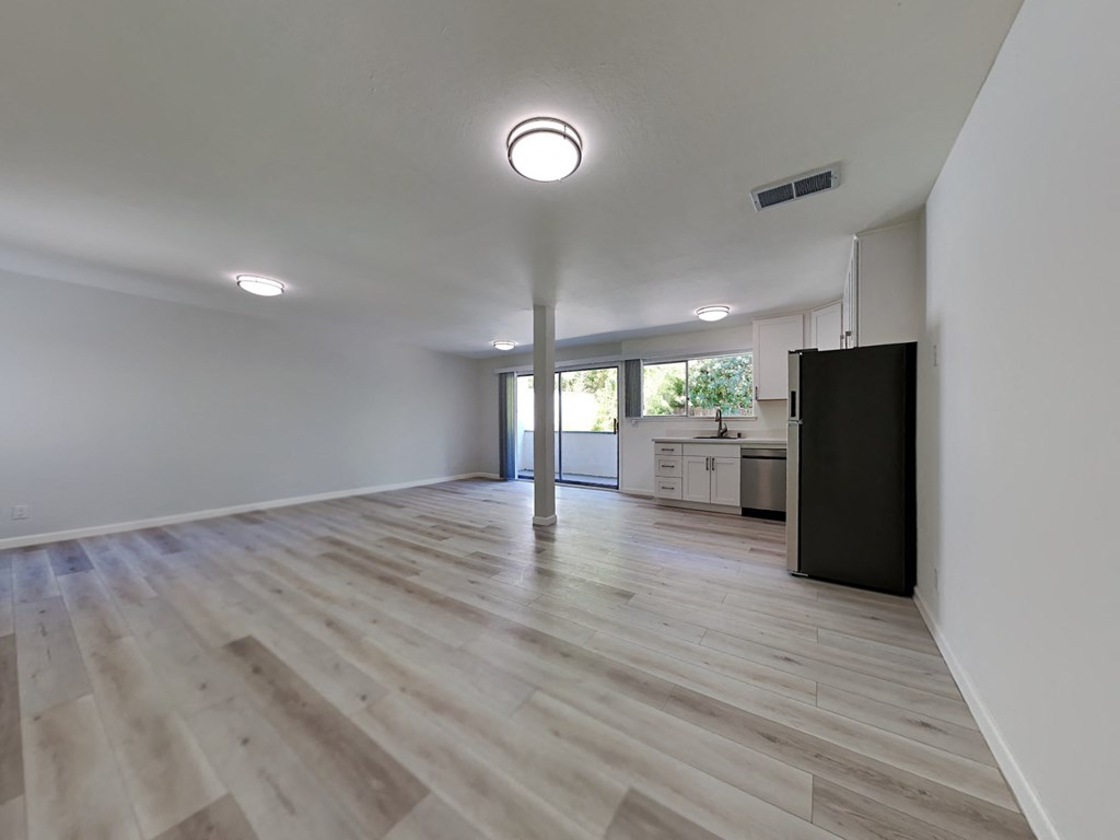an empty living room and kitchen with white walls and wood floors