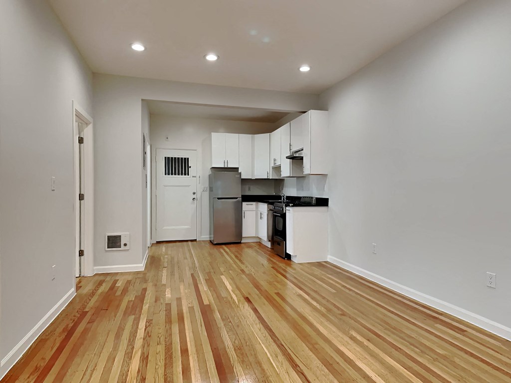 an empty living room and kitchen with wood flooring