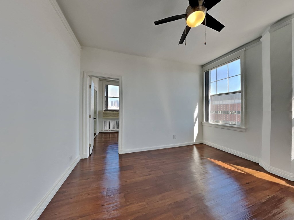 an empty living room with wood floors and a ceiling fan