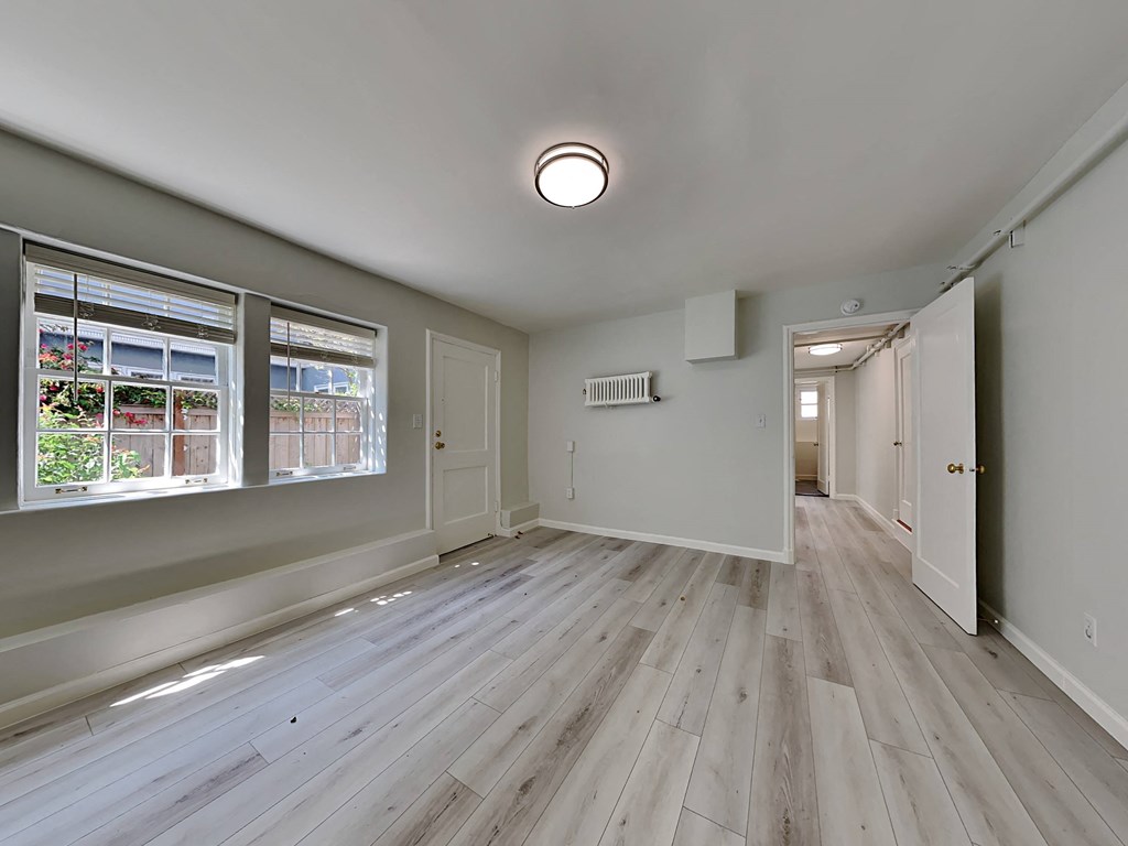 a renovated living room and hallway with wood floors and a large window
