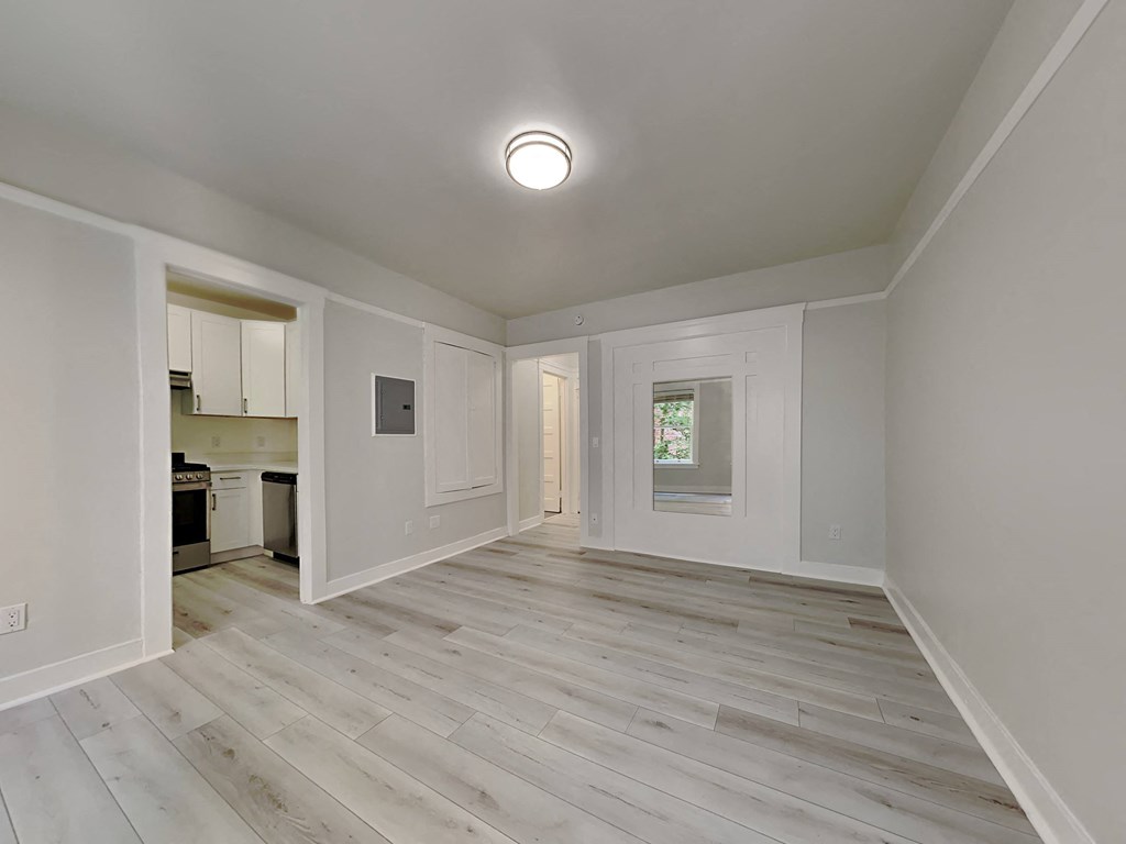 a renovated living room and kitchen with white walls and wood floors