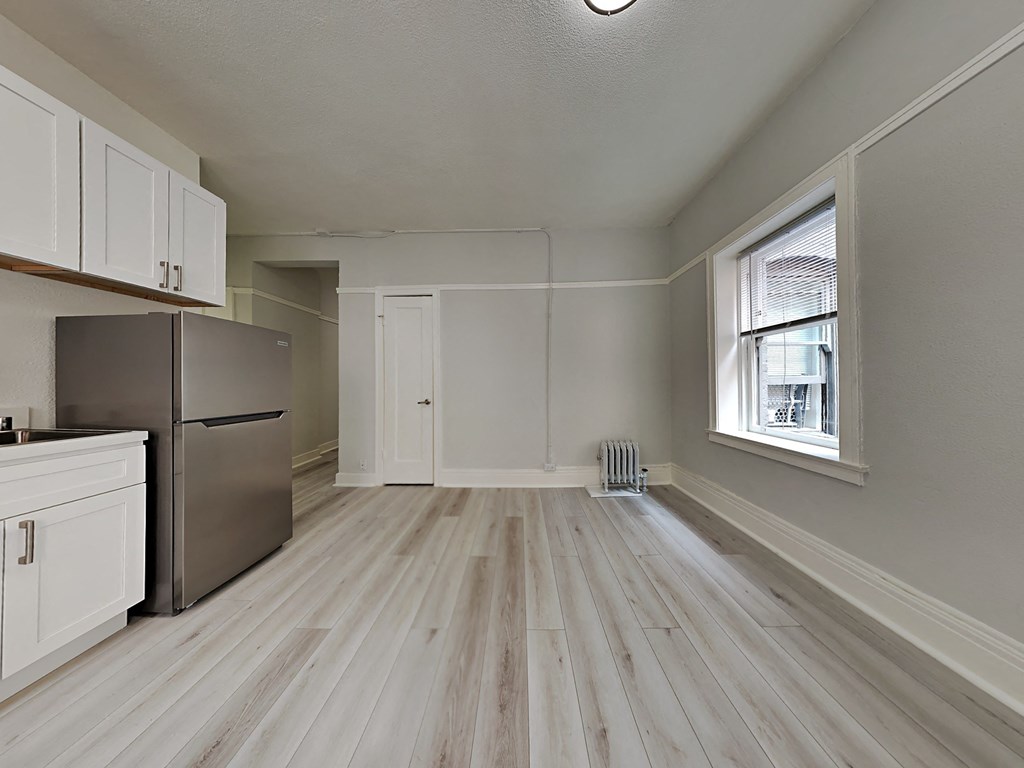 an empty kitchen with a refrigerator and a window