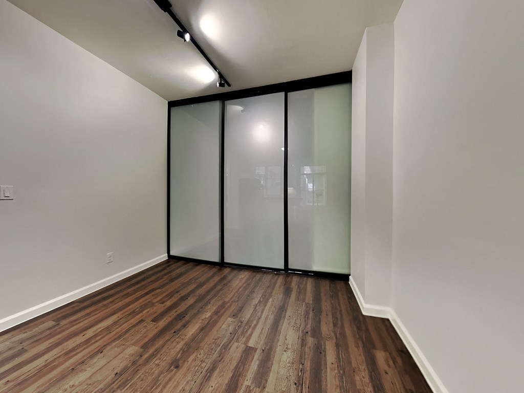 a room with white walls and wood floors and a sliding glass door